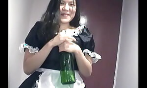 Young Oriental girl dressed as A a maid indulges herself with a bottle of champagne on camera for you